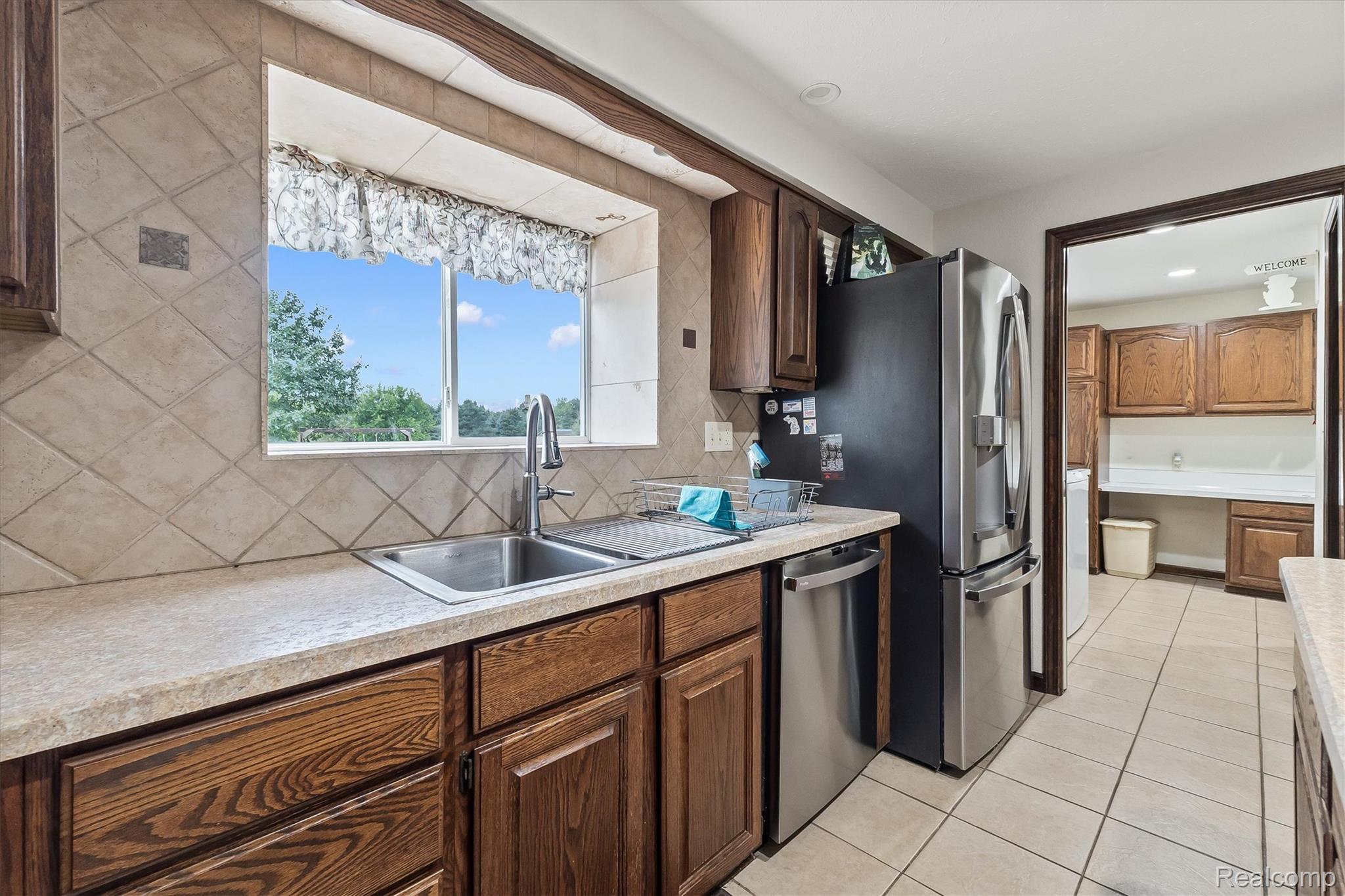 3553 North State Road Owosso, MI 48867 - Photo 14 of 45 Kitchen featuring wood cabinetry, a stainless steel sink with a high-arc faucet, and tiled backsplash