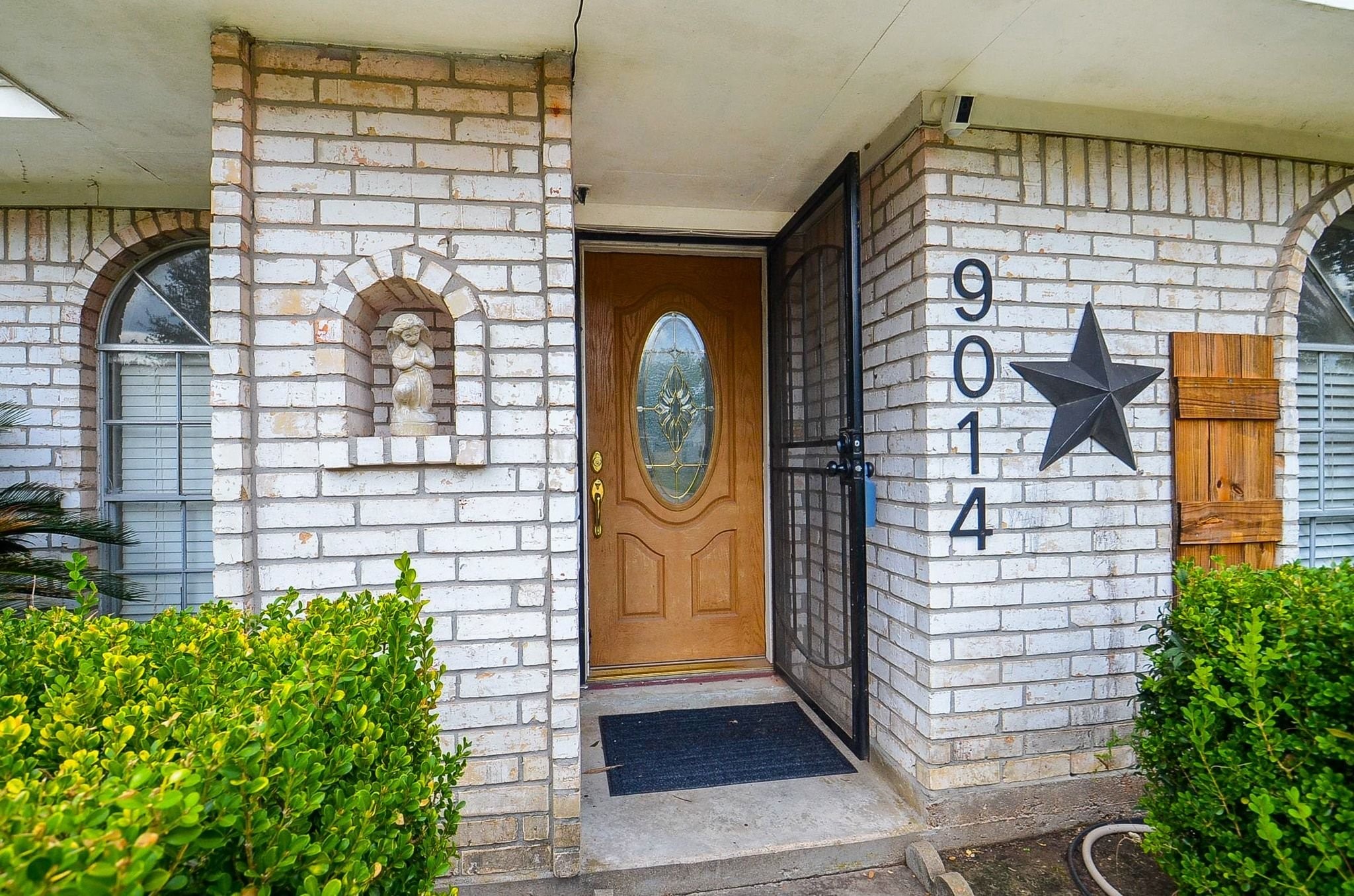 Step into a warm and welcoming entryway featuring a solid wood front door with decorative oval leaded glass and an added security screen door.