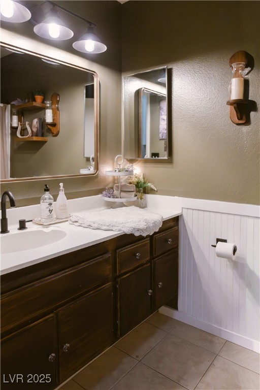 1515 Darlene Way Boulder City, NV 89005 - Photo 18 of 22 Full bathroom featuring double vanity, a wainscoted wall, light tile patterned flooring, and a textured wall