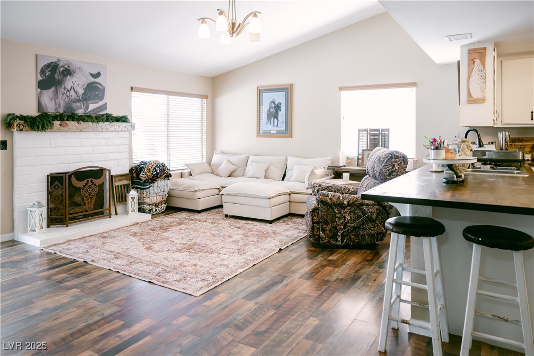 1515 Darlene Way Boulder City, NV 89005 - Photo 5 of 22 Living area with vaulted ceiling, a fireplace, dark wood-style floors, and a chandelier