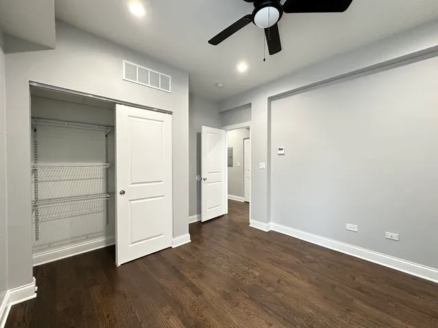 an empty room with wooden floor cabinet and windows