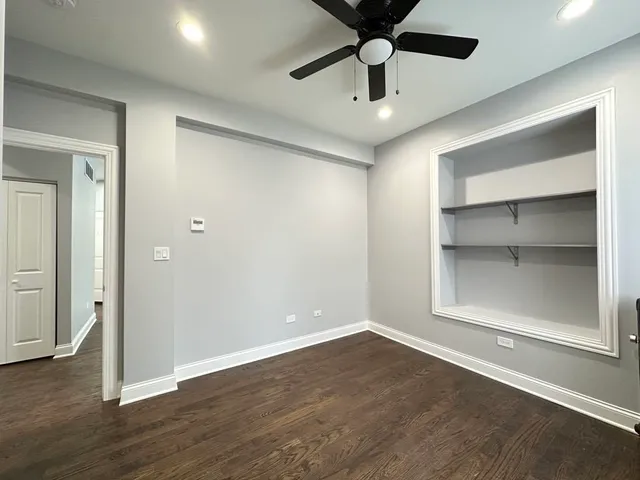 an empty room with wooden floor a ceiling fan and windows
