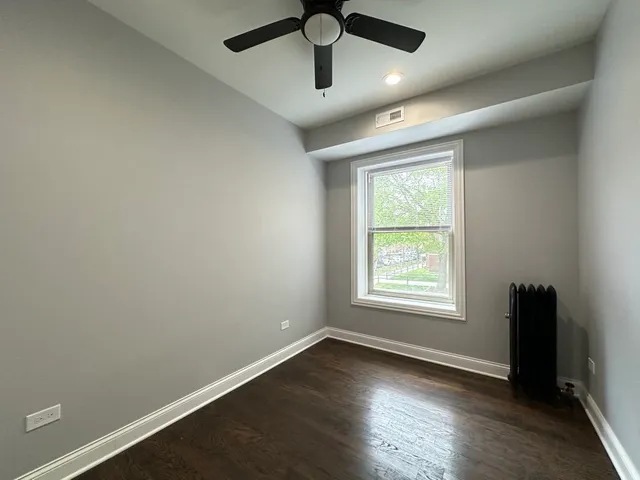 an empty room with wooden floor ceiling fan and windows