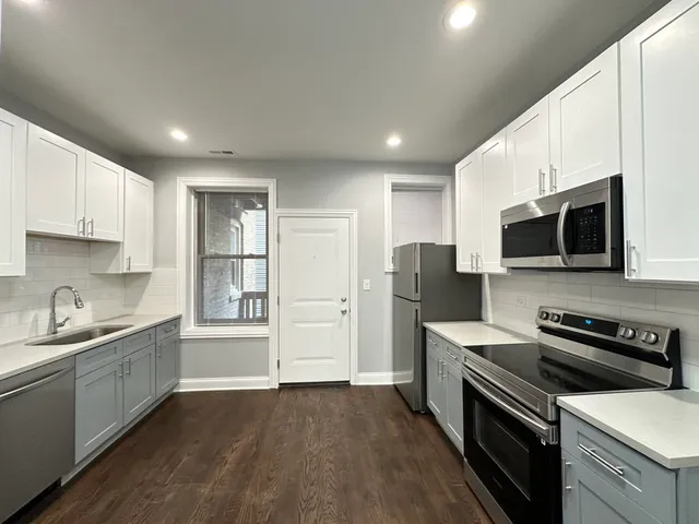 a kitchen with stainless steel appliances a sink a stove a microwave a refrigerator a cabinets and wooden floor