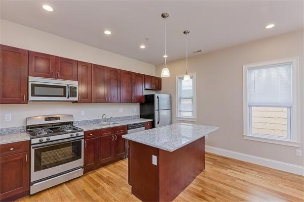 a kitchen with stainless steel appliances granite countertop wooden cabinets a stove top oven a sink and dishwasher with wooden floor