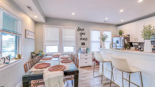 a very nice looking dining room with kitchen island furniture a large window and a refrigerator