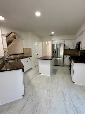 a large white kitchen with a sink and a stove top oven