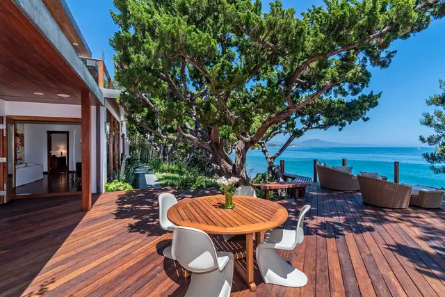 a backyard of a house with wooden floor table and chairs