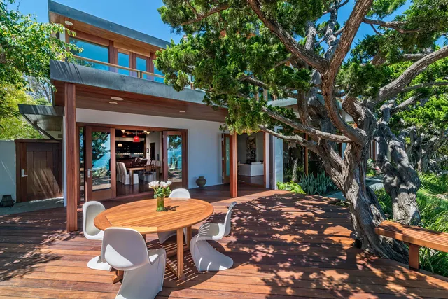a view of a patio with table and chairs potted plants and large tree