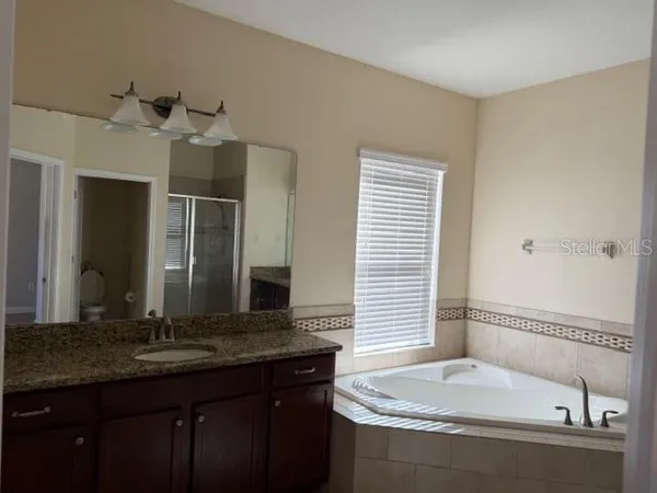 a bathroom with a granite countertop sink and a bathtub