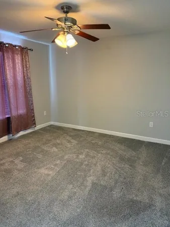 a view of an empty room with a chandelier fan