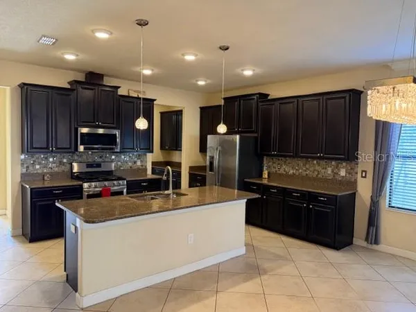 a kitchen with stainless steel appliances granite countertop a refrigerator and a stove top oven