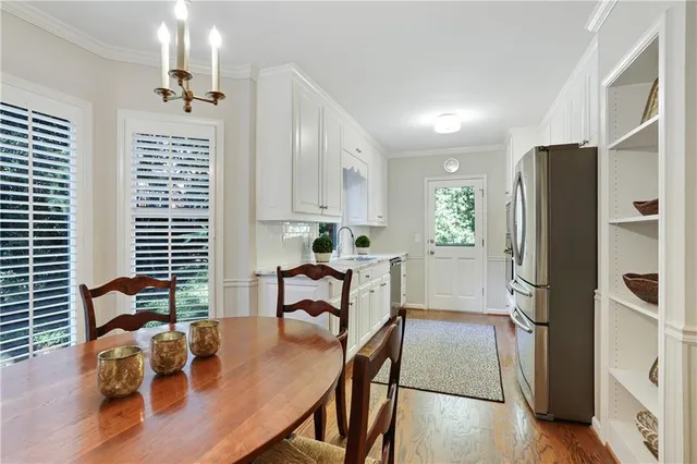 a kitchen with stainless steel appliances granite countertop a refrigerator a stove a sink dishwasher and white cabinets with wooden floor