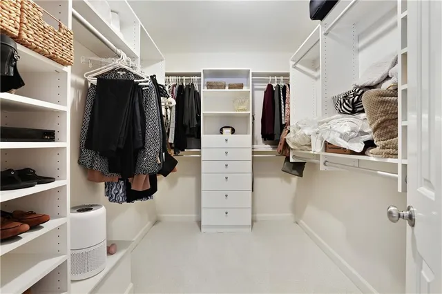 a view of walk in closet with clothes and shoes