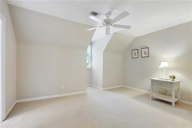 an empty room with a chandelier fan and windows
