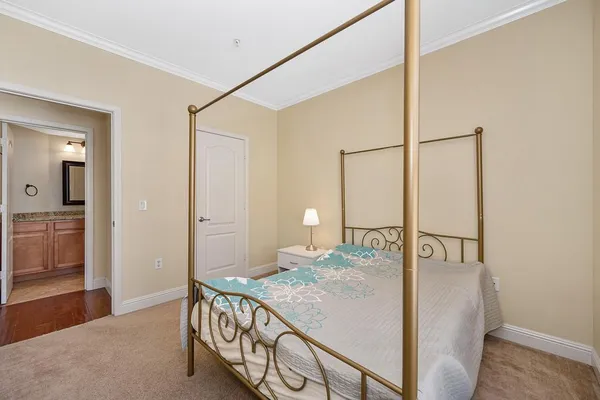 a bedroom with a bed a table and painting on the wall