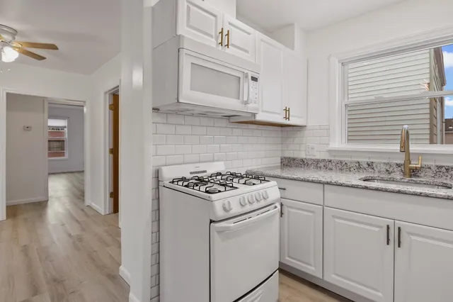 a kitchen with granite countertop white cabinets and white appliances