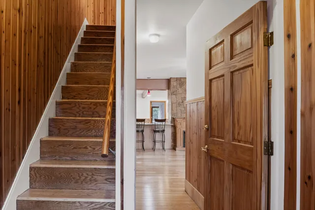 a view of a hallway to a livingroom with wooden floor and stairs