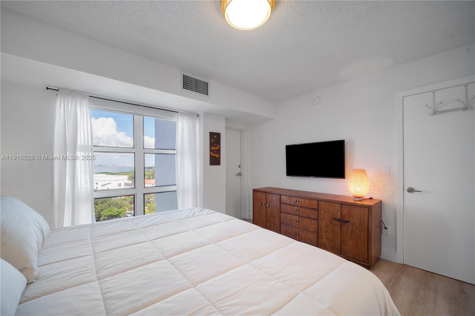 77 Crandon Boulevard, Unit 10C Key Biscayne, FL 33149 - Photo 18 of 37 a bedroom with a bed and a television