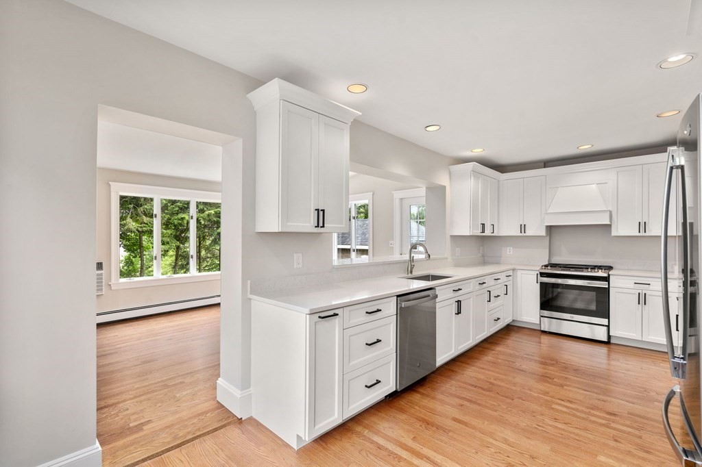 95 Russett Road Boston, MA 02132 - Photo 14 of 42 a kitchen with stainless steel appliances granite countertop a stove a sink dishwasher a refrigerator white cabinets and wooden floor next to a window