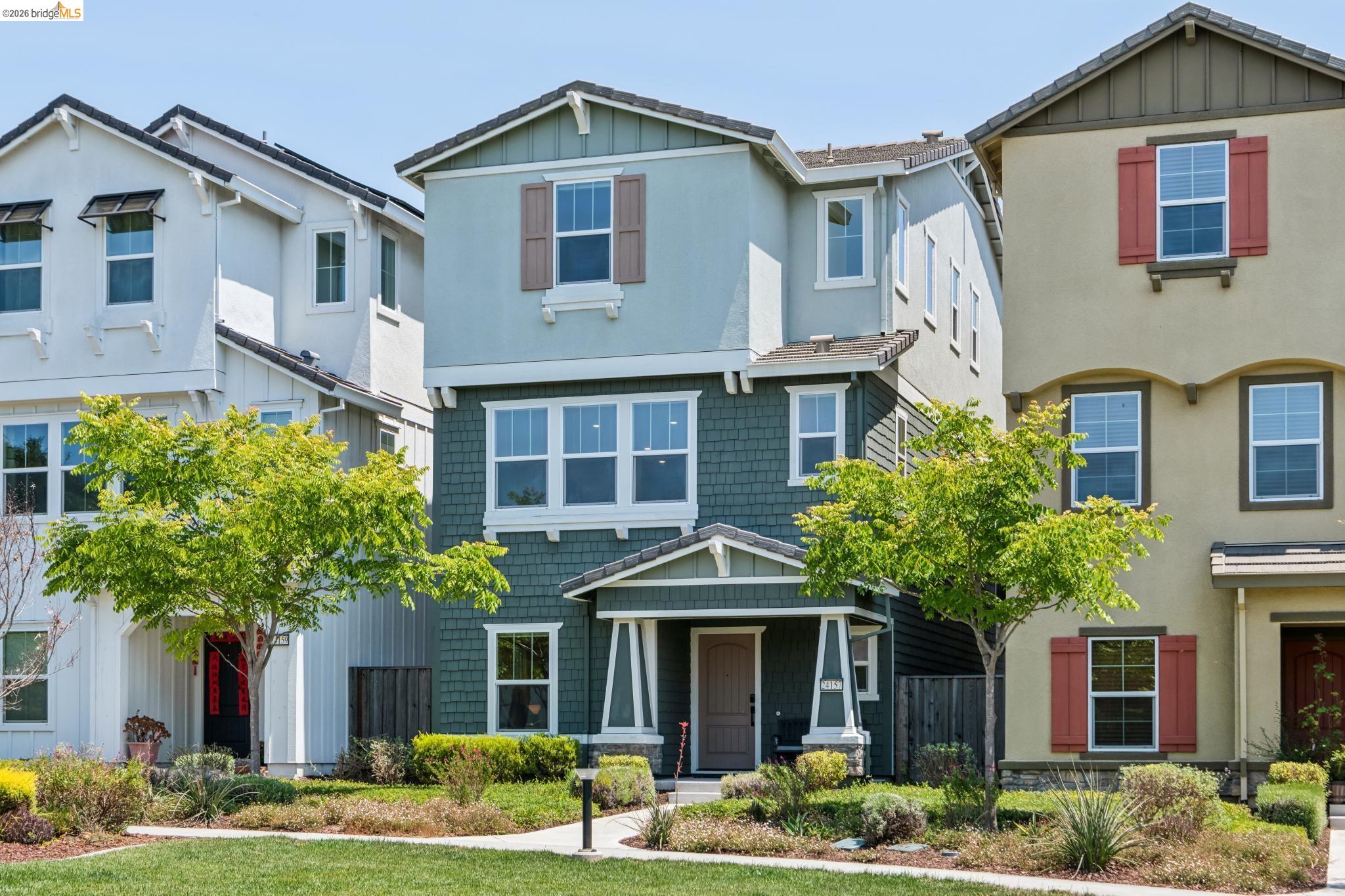24157 Amaranth Loop Hayward, CA 94541 - Photo 3 of 63 Three-story residence featuring a covered entry porch with columns, a mix of horizontal siding and shingle siding, multiple windows, and a mature tree in the front landscaping
