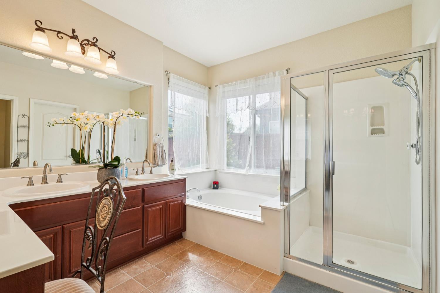 164 Legacy Street Manteca, CA 95337 - Photo 28 of 33 a bathroom with a double vanity sink a mirror a bathtub and next to a window