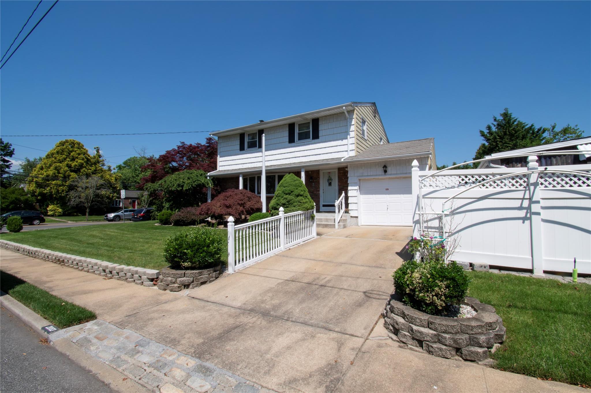 2083 Elm Place Merrick, NY 11566 - Photo 1 of 1 Traditional home featuring a garage, concrete driveway, and covered porch