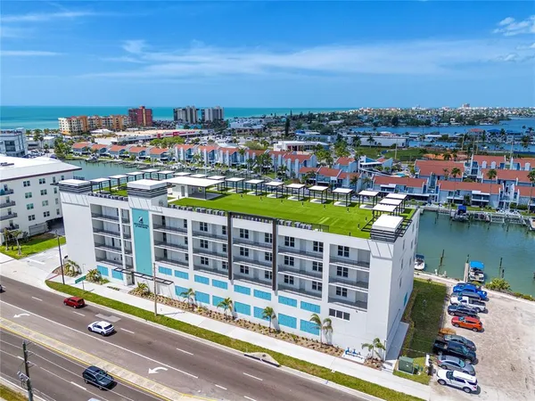 a front view of a building with lot of cars and trees