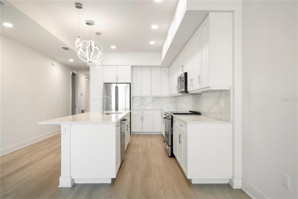 400 150th Avenue, Unit 501 Madeira Beach, FL 33708 - Photo 40 of 76 a kitchen that has a lot of white cabinets and stainless steel appliances