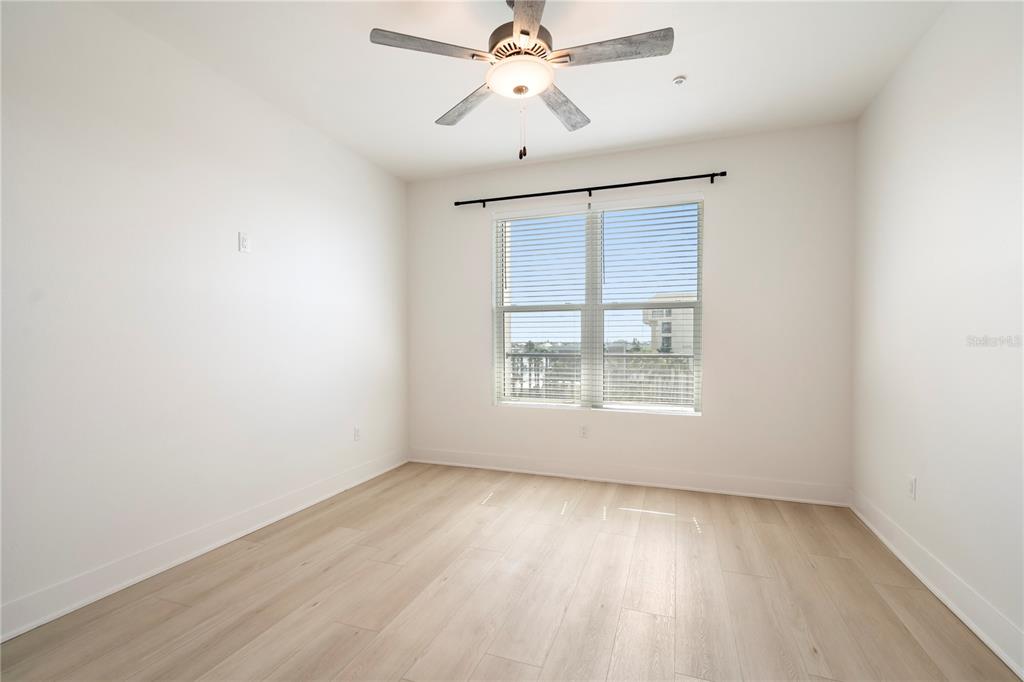 400 150th Avenue, Unit 501 Madeira Beach, FL 33708 - Photo 51 of 76 an empty room with wooden floor ceiling fan and windows
