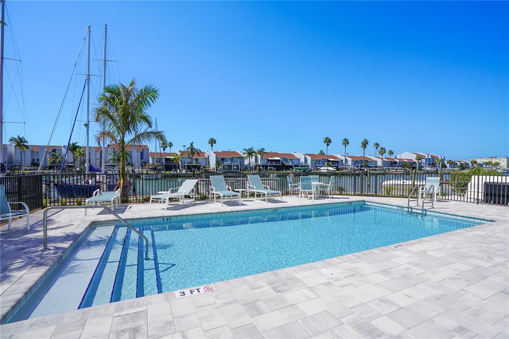 400 150th Avenue, Unit 501 Madeira Beach, FL 33708 - Photo 9 of 76 a view of a swimming pool with a lawn chairs under an umbrella