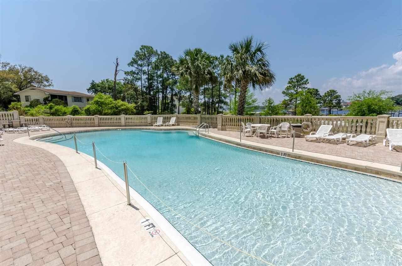 13928 River Road, Unit 504 Perdido Key, FL 32507 - Photo 33 of 40 a view of a swimming pool with a lawn chairs and palm trees