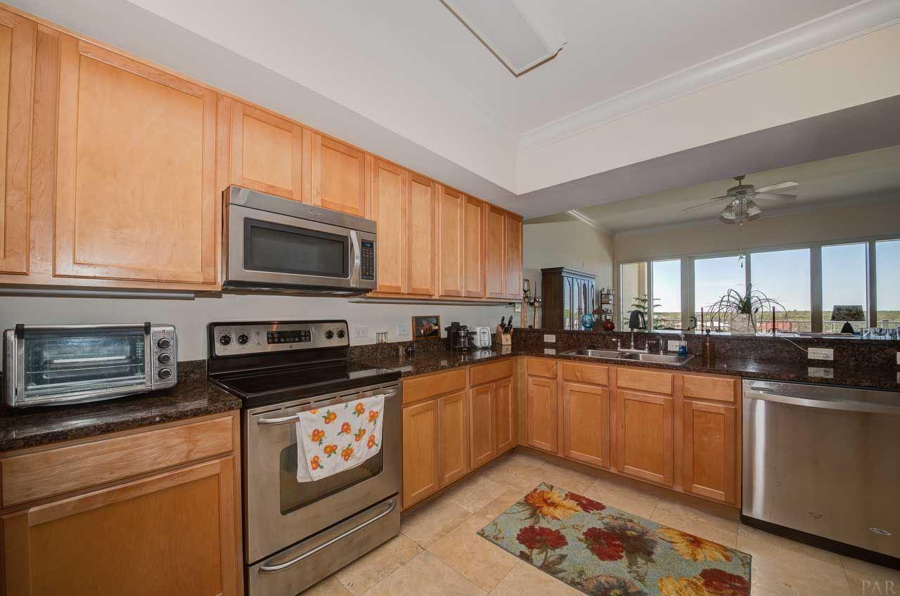 13928 River Road, Unit 504 Perdido Key, FL 32507 - Photo 4 of 40 a kitchen with stainless steel appliances kitchen island granite countertop a sink dishwasher stove and microwave with wooden cabinets