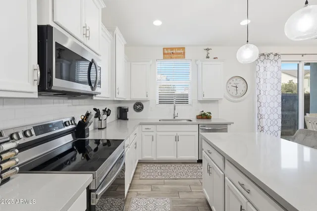 a kitchen with stainless steel appliances granite countertop a sink a stove a refrigerator and island with wooden floor