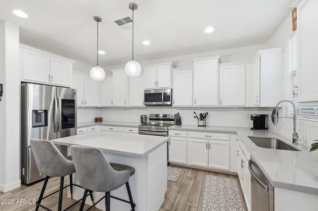 a kitchen that has a table chairs stainless steel appliances and cabinets