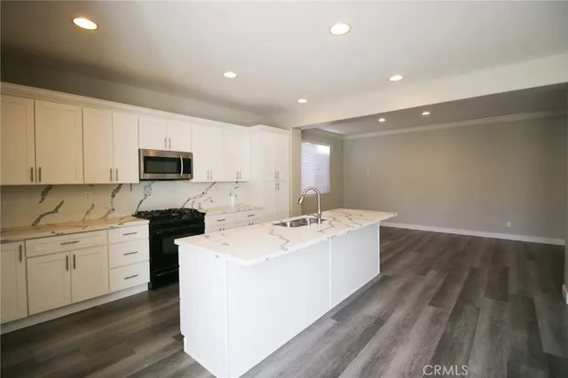 a large white kitchen with sink a microwave and cabinets