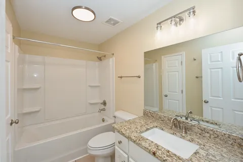 a bathroom with a granite countertop sink a toilet and shower