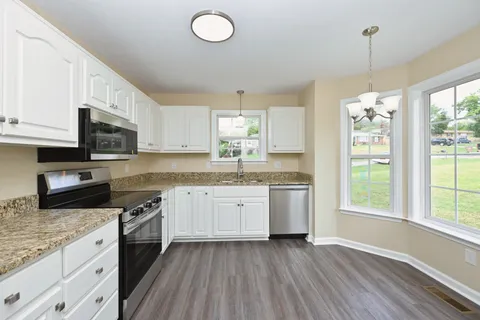a kitchen with granite countertop cabinets stainless steel appliances a sink and a window