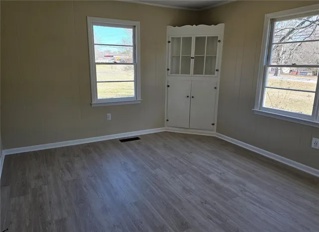 an empty room with wooden floor and windows