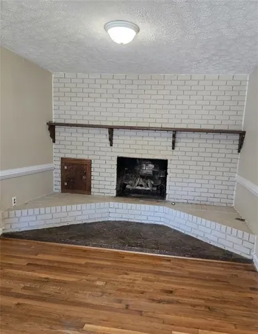 a view of an empty room with wooden floor and a fireplace