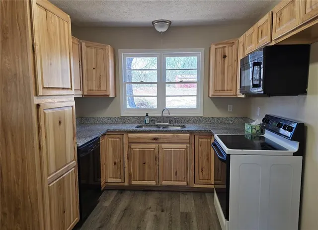 a kitchen with granite countertop a sink stainless steel appliances and cabinets