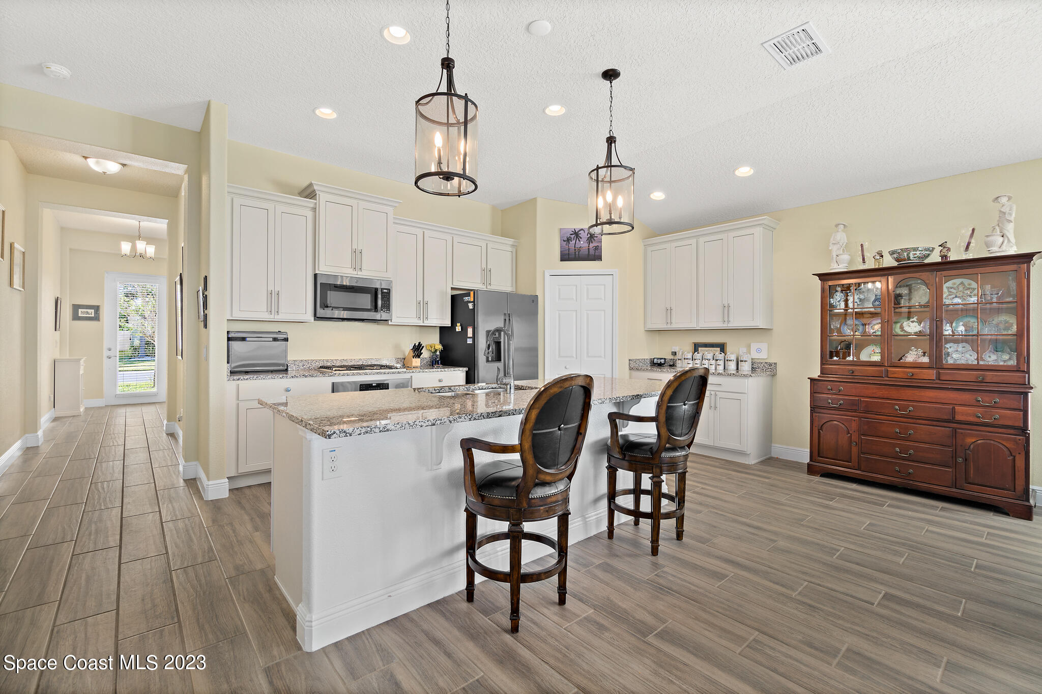 4465 Ruthann Circle Melbourne, FL 32934 - Photo 2 of 42 a kitchen with stainless steel appliances kitchen island granite countertop a refrigerator a stove a sink dishwasher and a dining table with wooden floor