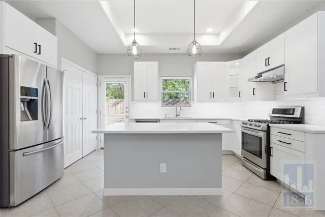 a kitchen with white cabinets and stainless steel appliances