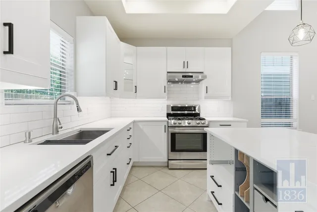 a kitchen with cabinets stainless steel appliances and a chandelier