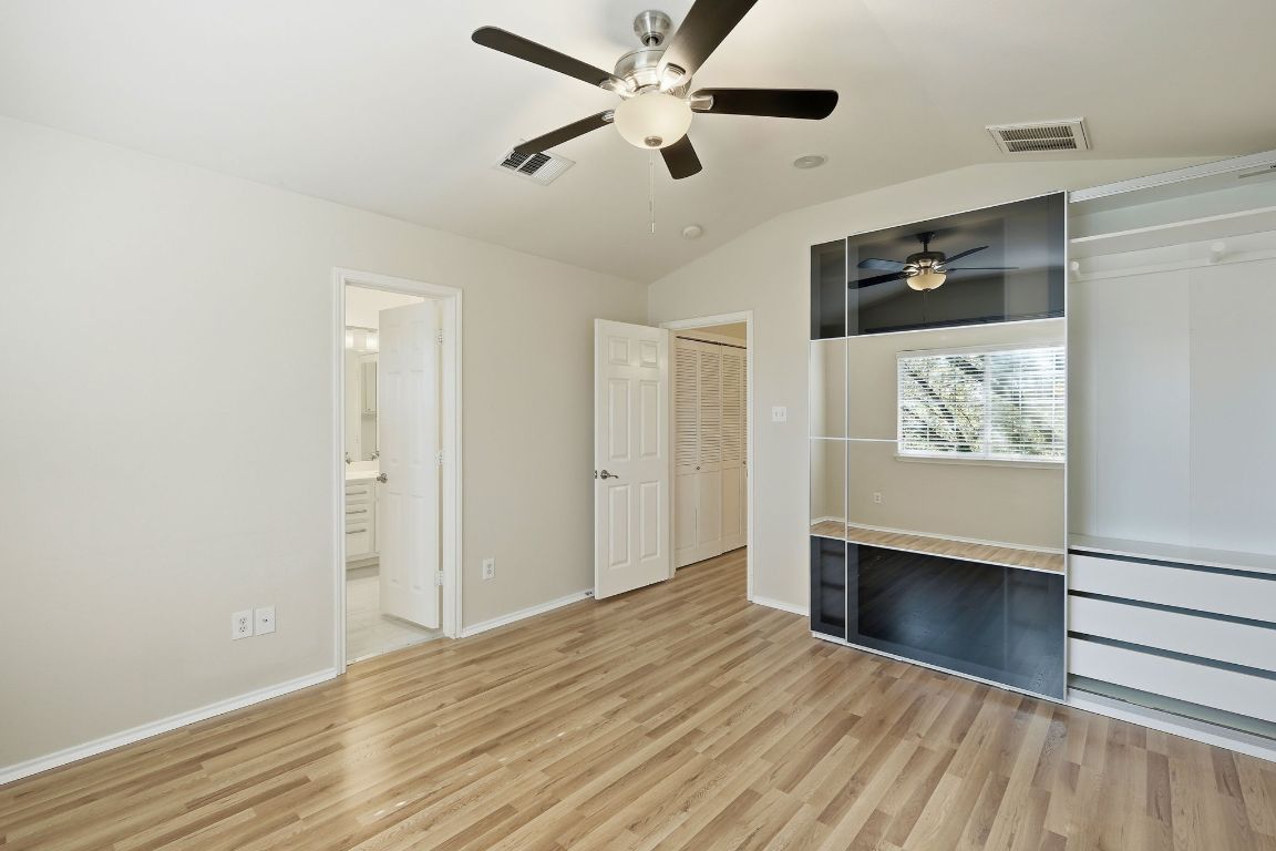 1900 Scofield Ridge Parkway, Unit 203 Austin, TX 78727 - Photo 16 of 31 Unfurnished bedroom featuring ceiling fan, light wood finished floors, lofted ceiling, a closet, and connected bathroom