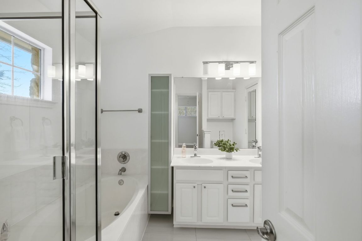 1900 Scofield Ridge Parkway, Unit 203 Austin, TX 78727 - Photo 17 of 31 Bathroom with double vanity, a garden tub, a shower stall, lofted ceiling, and light tile patterned flooring