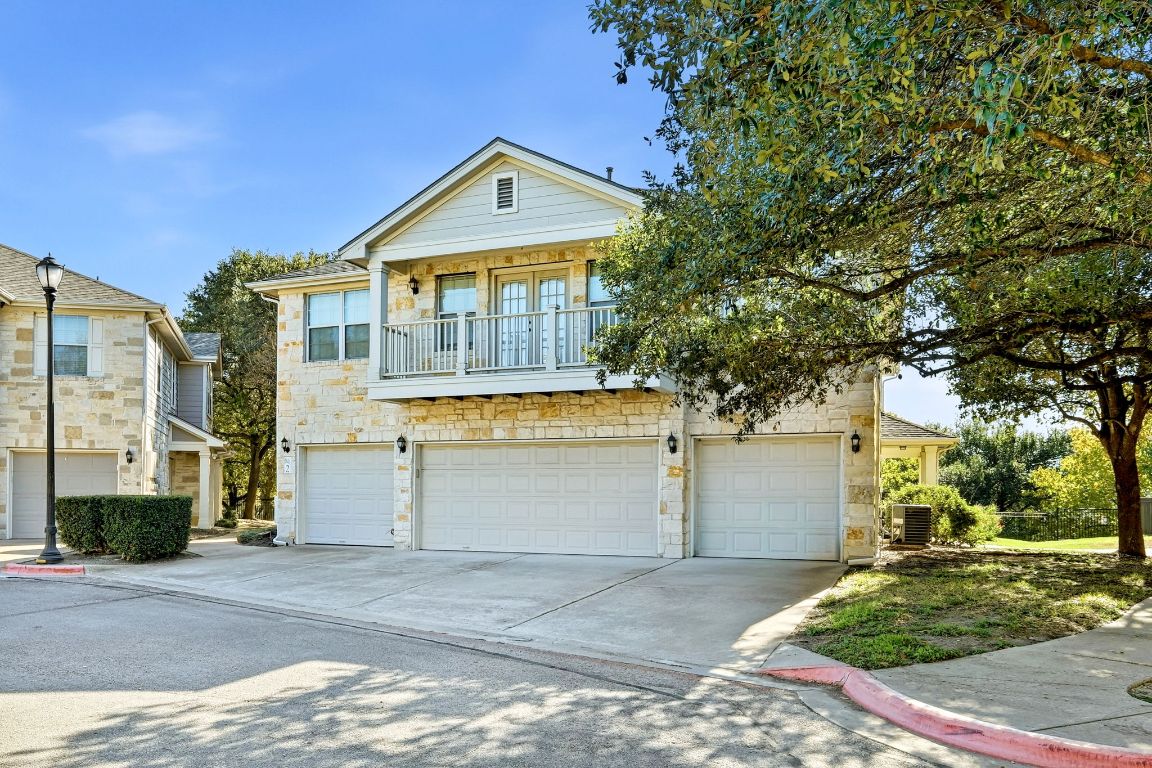 1900 Scofield Ridge Parkway, Unit 203 Austin, TX 78727 - Photo 2 of 31 View of front of house featuring a balcony, stone siding, concrete driveway, and a garage