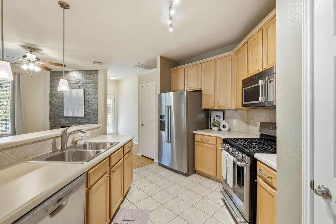1900 Scofield Ridge Parkway, Unit 203 Austin, TX 78727 - Photo 9 of 31 Kitchen featuring light brown cabinets, appliances with stainless steel finishes, light countertops, and decorative light fixtures