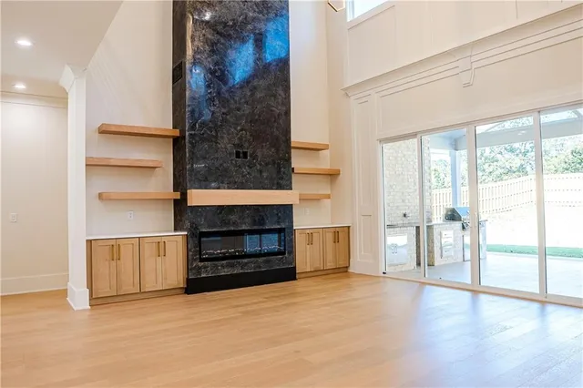 a view of an empty room with wooden floor fireplace and a window