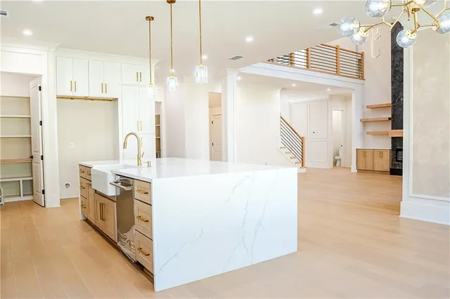 a large kitchen with stainless steel appliances kitchen island granite countertop a refrigerator a oven and a wooden floors